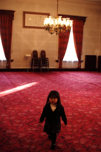 a little girl walks on a red carpeted floor