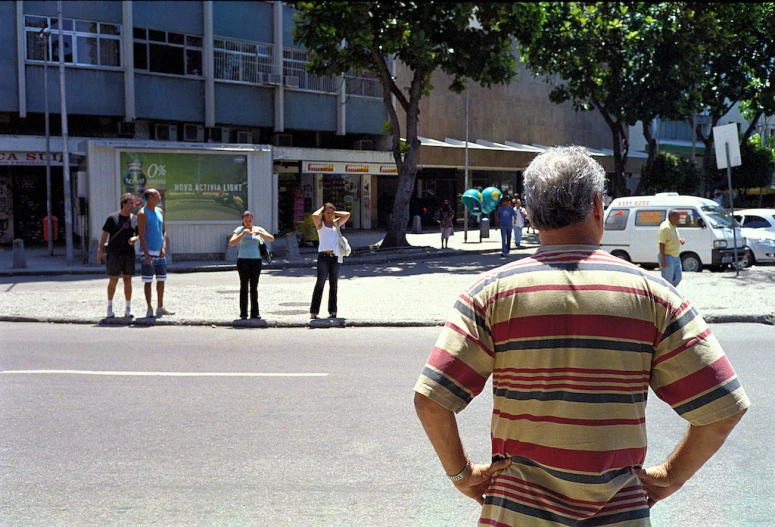 a group of people standing on the side of a road near tall buildings