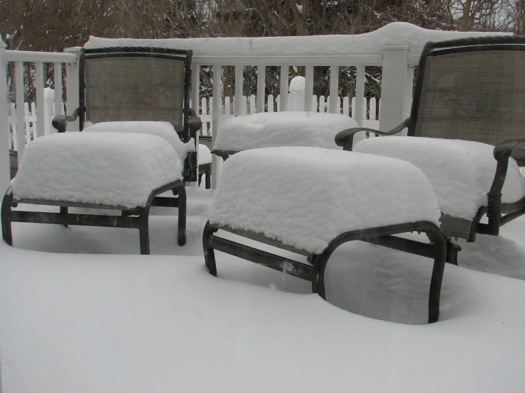 there are four empty chairs on this deck in the snow