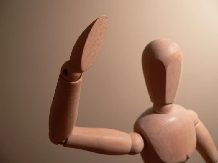 a wooden mannequin holds up a knife while standing