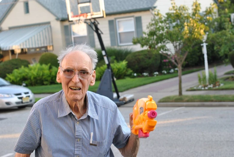 an old man holding a plastic toy animal in his left hand