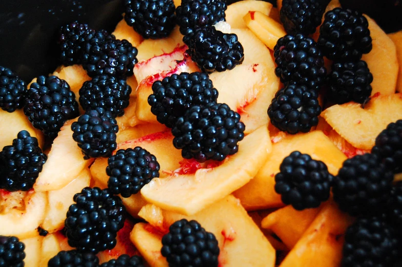 fresh berries and sliced peaches are arranged together