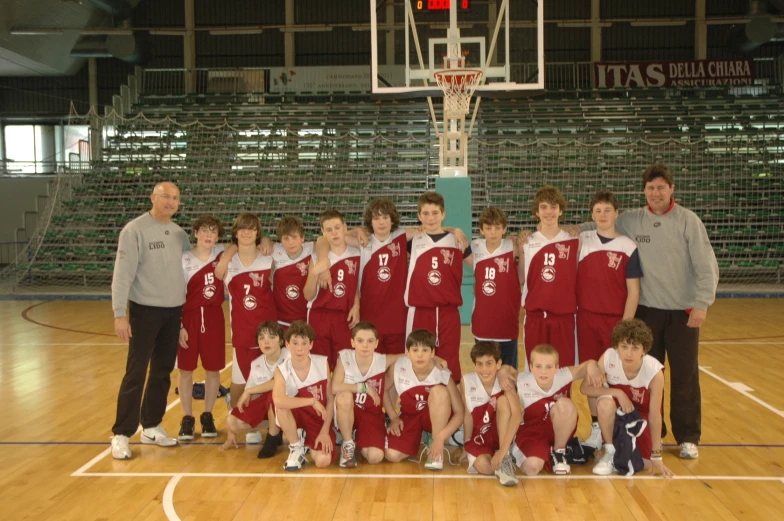 a basketball team with two men in the middle and some boys sitting on the sidelines