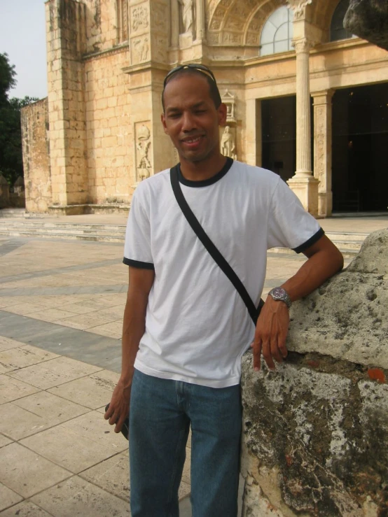 a man standing with a white shirt and black cross