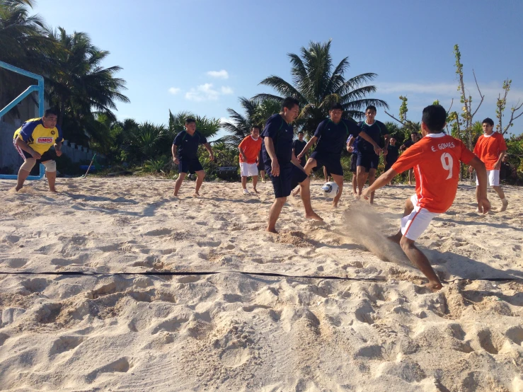 a group of young men playing soccer on top of sand