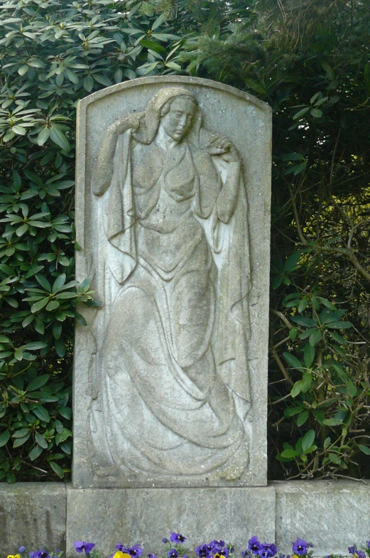 statue of woman standing in garden with purple flowers