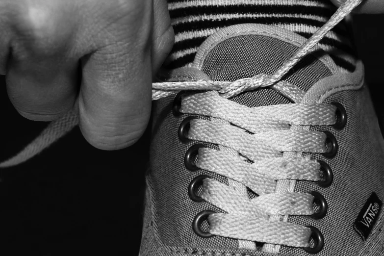 an unmade shoelaced sneaker being held by a person