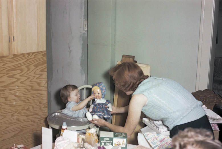 woman feeding baby a toy on chair next to a christmas tree