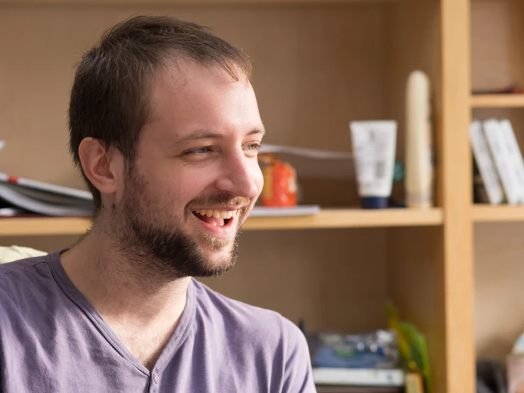 a guy smiling while sitting in a chair