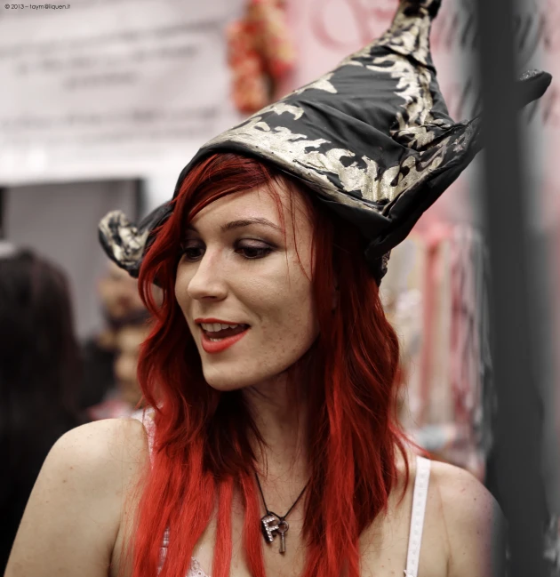 a young woman with red hair wears a halloween witch hat