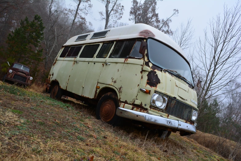 a dirty and rusted bus is parked on the side of the hill