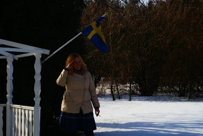 a woman holding onto a flag while walking in the snow