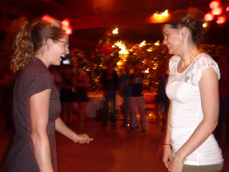 two woman talk to each other while talking at a party