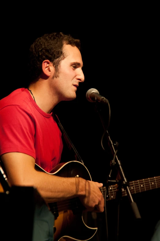 a man holding a guitar and a microphone at a show