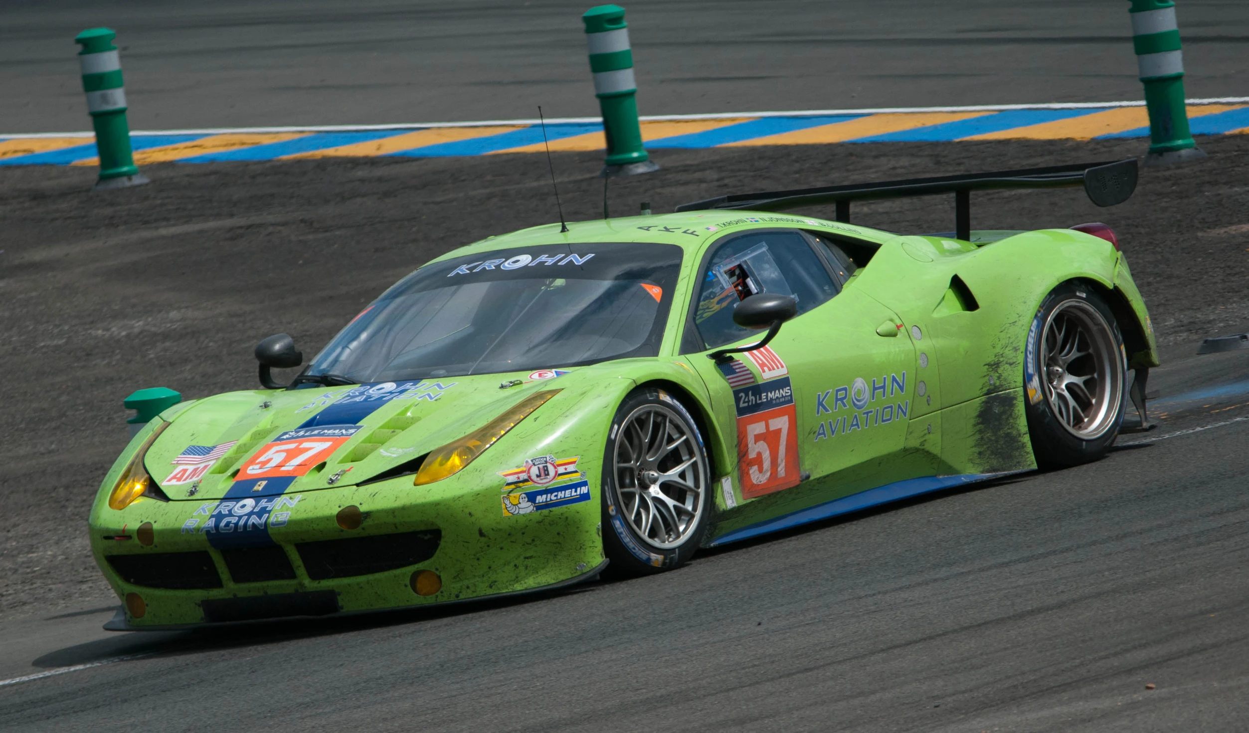 the green sports car is racing down a track