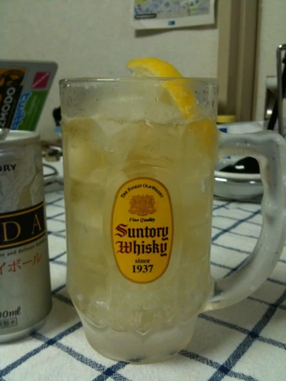 an alcoholic drink with an empty can and lemon wedges next to it