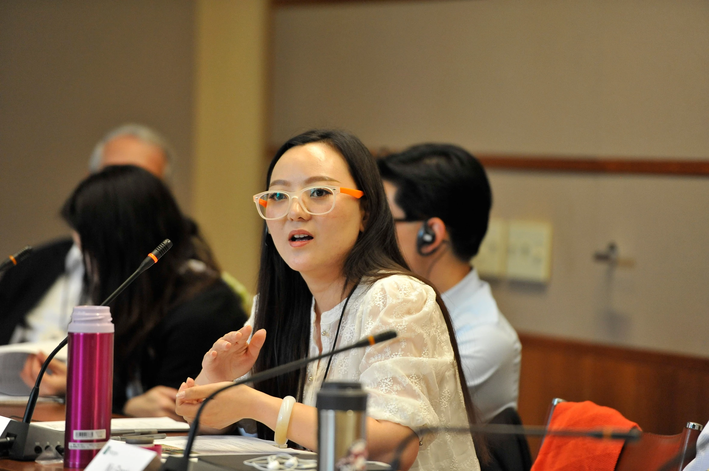 asian woman sitting at a table and listening to someone