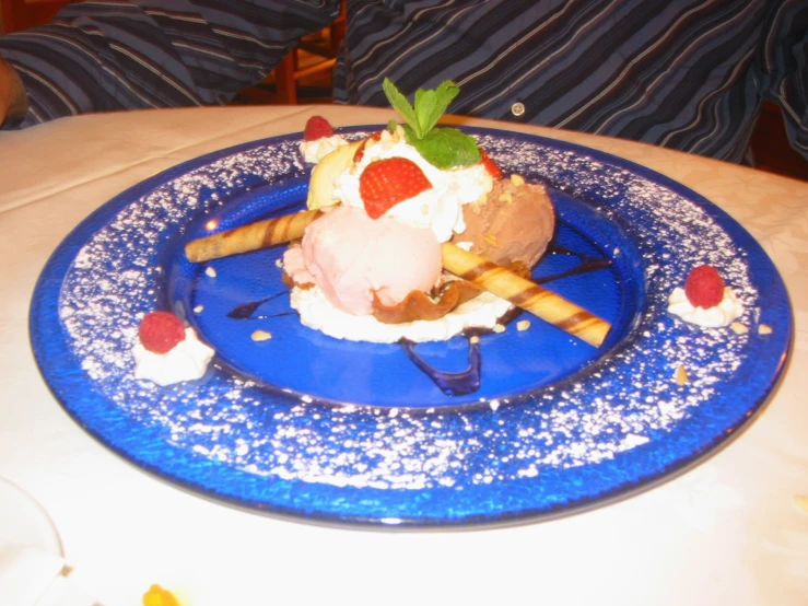 a blue plate topped with strawberries, ice cream and whip