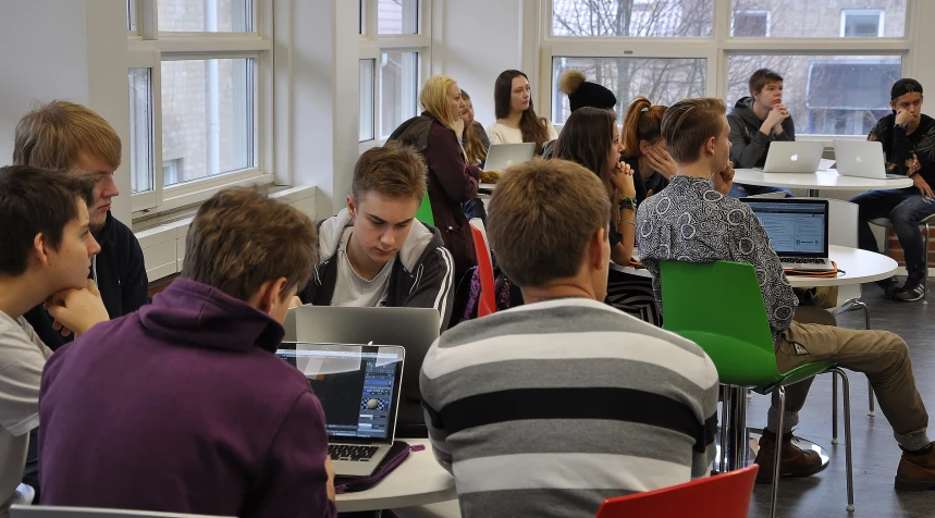 a room filled with students sitting at laptop computers