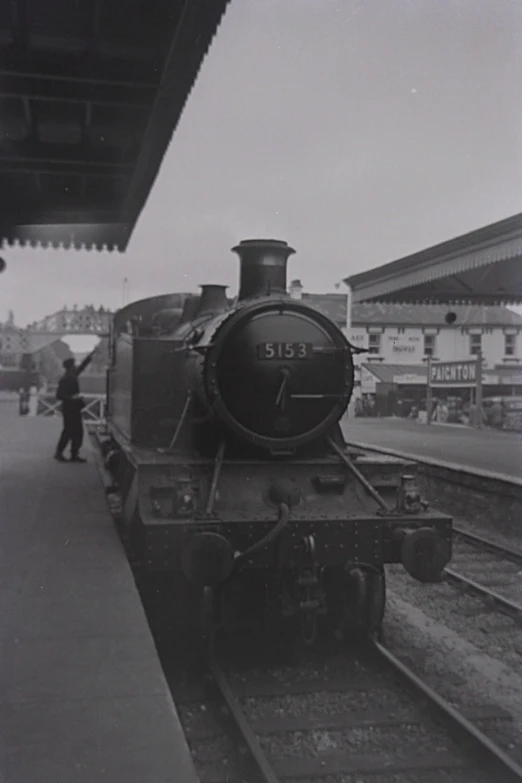 an old locomotive is on the tracks in front of a train station