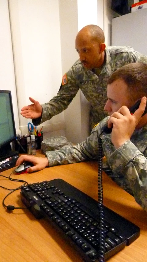 two soldiers sitting at a table talking on the phone