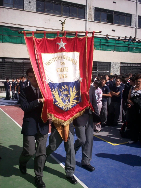 two men walking down a walkway holding a large red and white banner