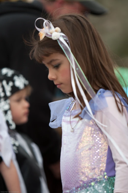 a little girl in dress with white ribbon around her head