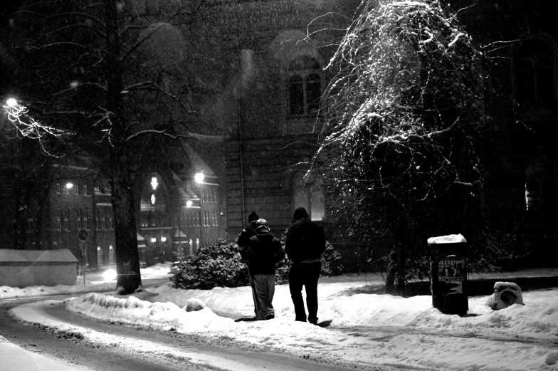 a couple of people standing on a snow covered sidewalk