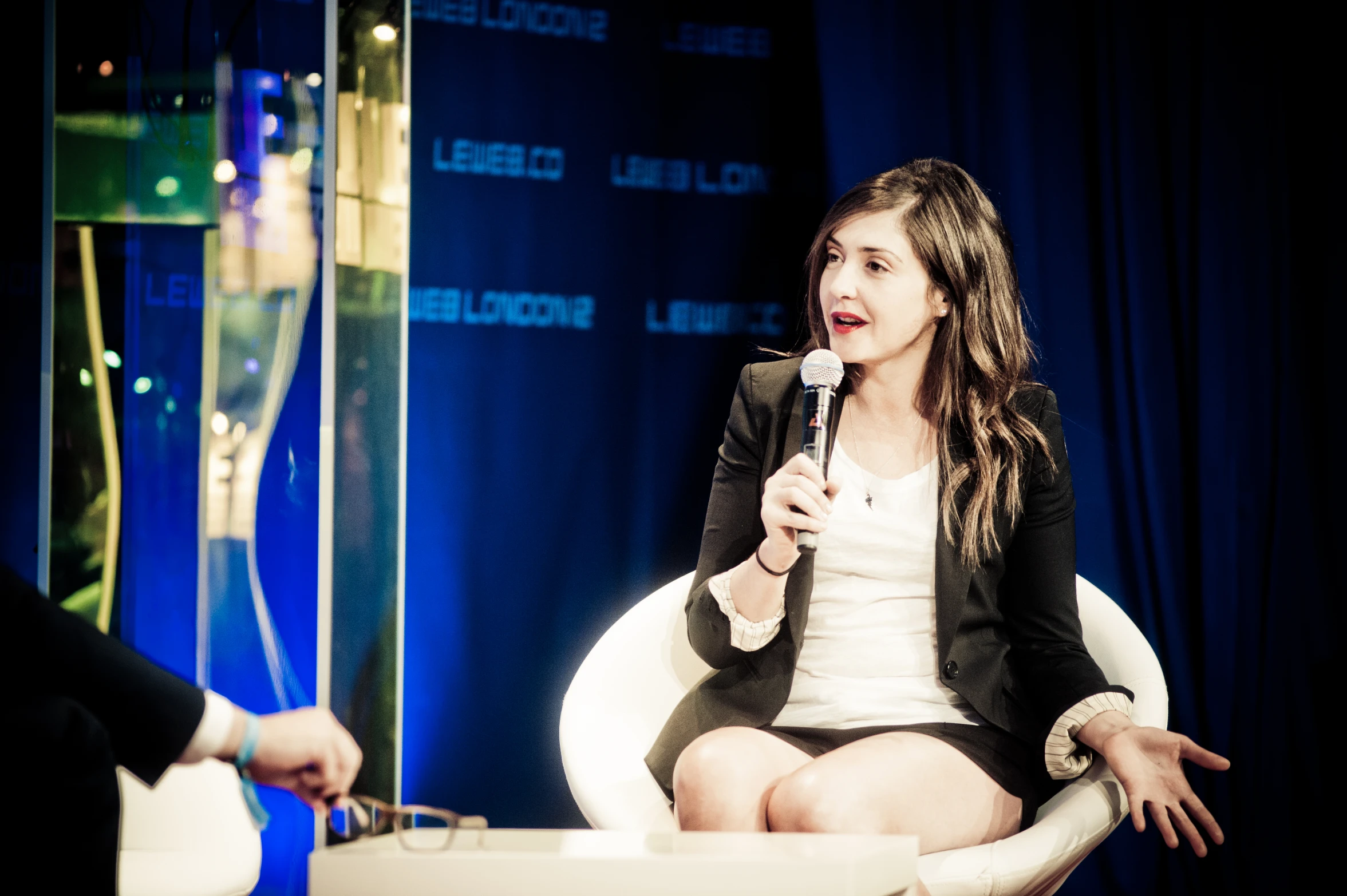 a woman sitting in a white chair holding a microphone