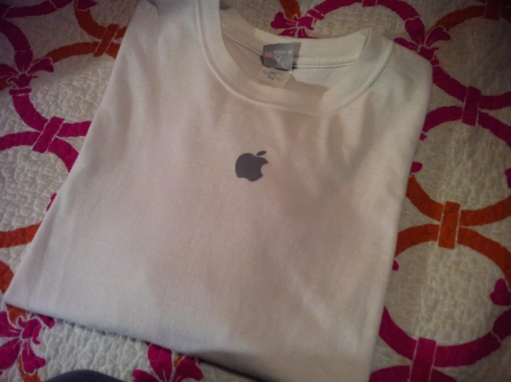 a t - shirt with an apple icon on it is laying on a bed