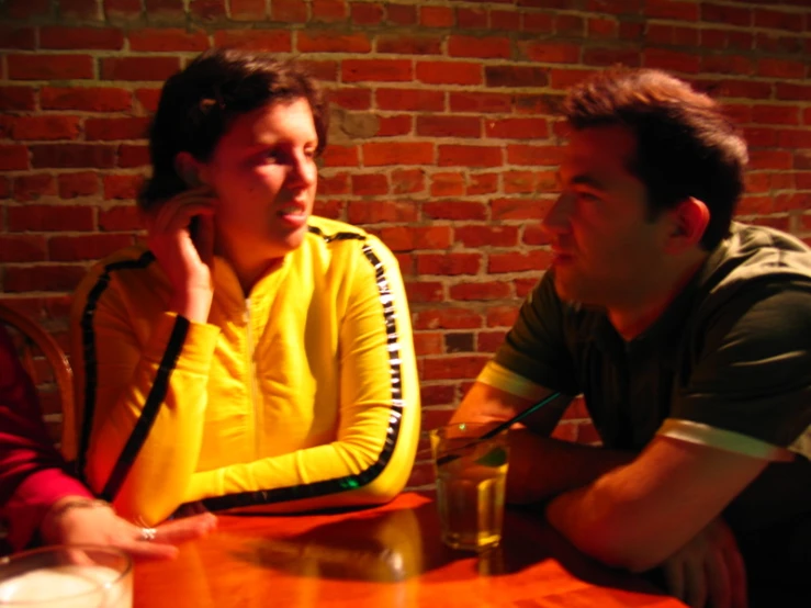 two people sit at a table, talking