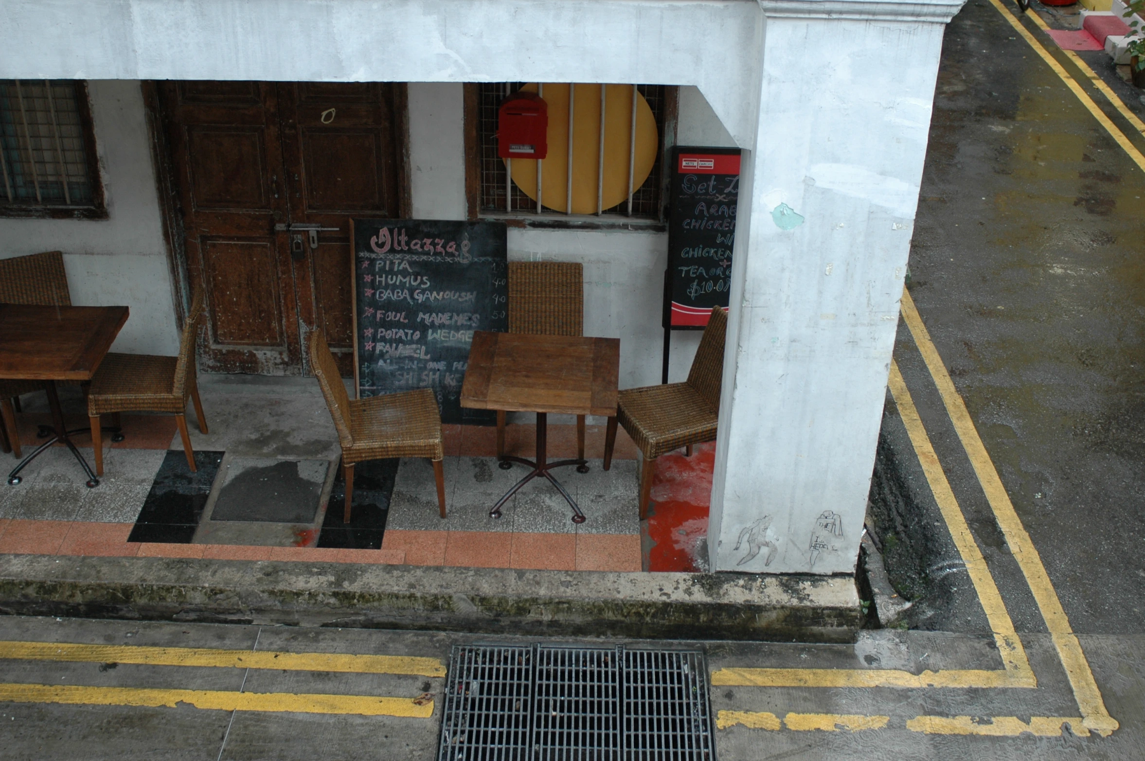 some brown chairs a blackboard a sidewalk and a yellow caution line