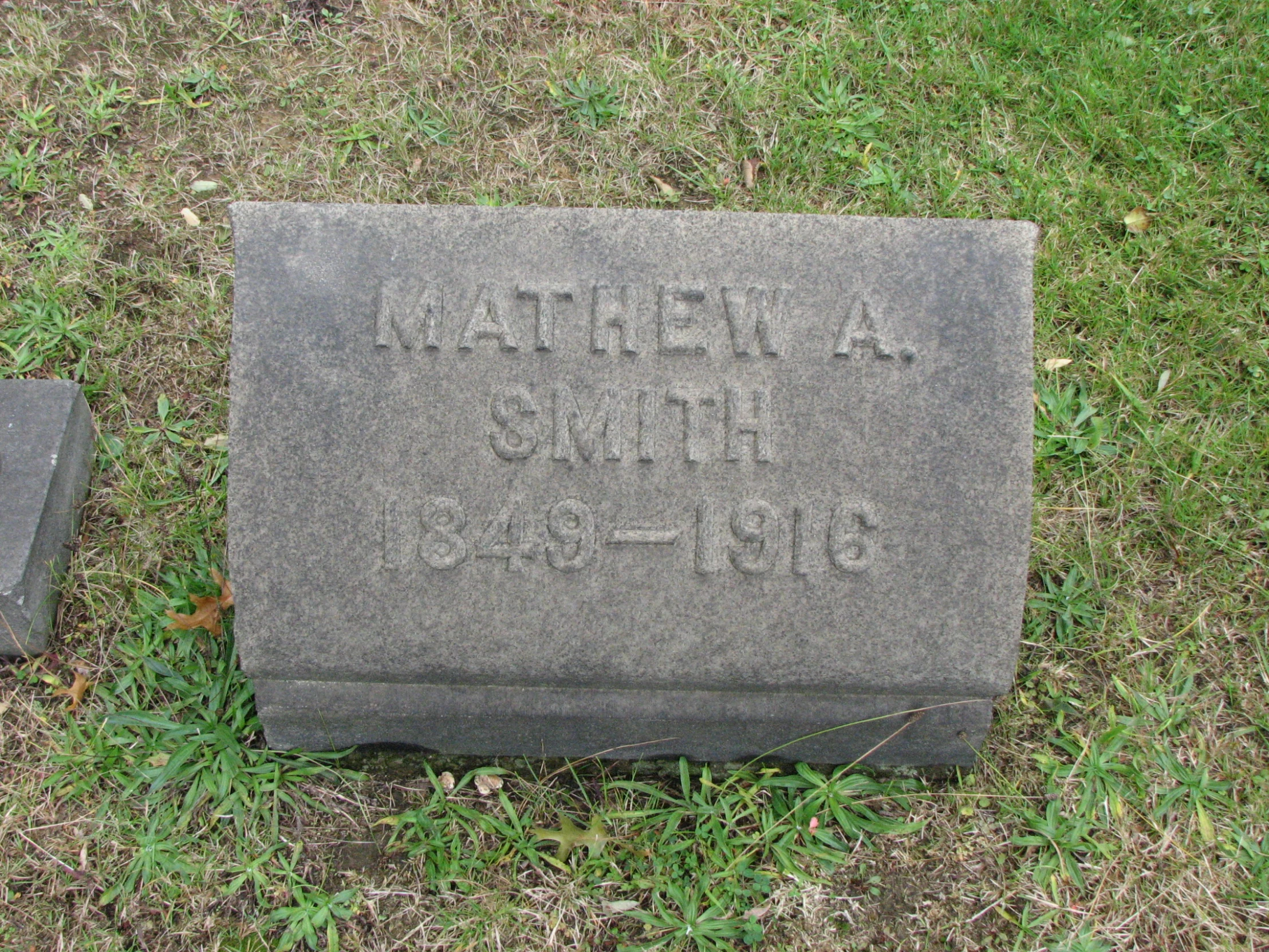 a headstone is on the grass with two cement blocks