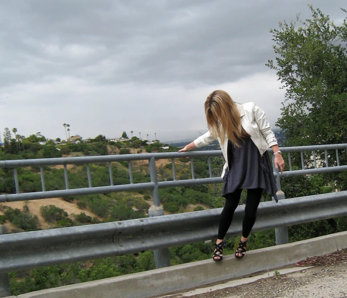 a woman standing on top of a bridge next to trees