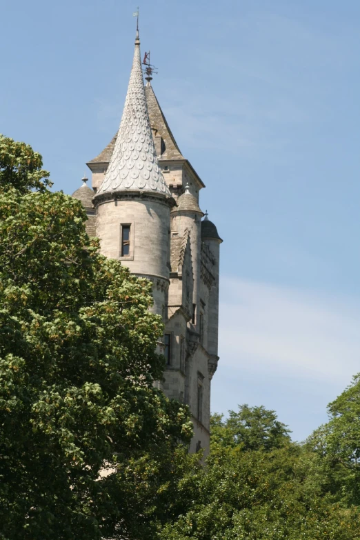 a tower with a clock on the top is surrounded by green trees