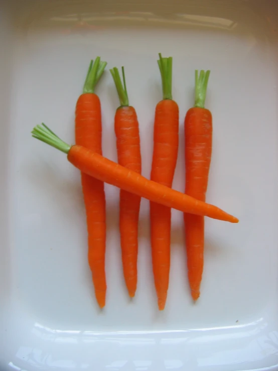several small carrots in a bowl on a white surface
