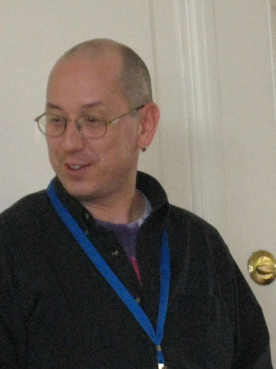 a man wearing glasses and a black suit stands in a doorway