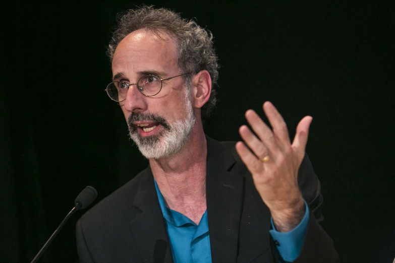 the man is speaking at an event with his hands out