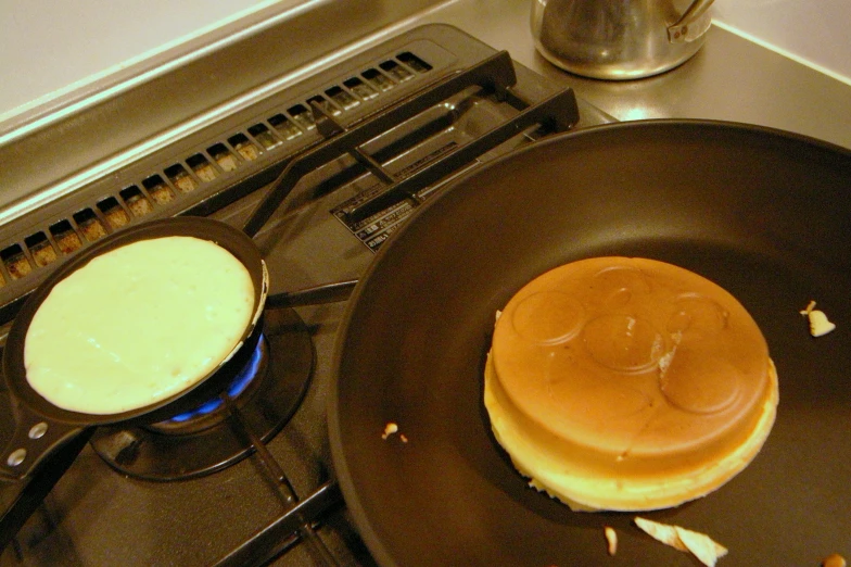 a burger cooking on top of a pan over an open burner