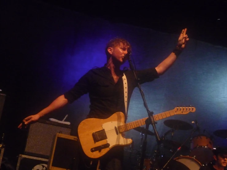 a person standing next to a microphone with his hand in the air