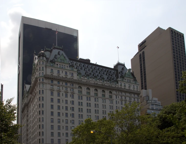 a white skyscr with green rooftops stands behind another high rise building