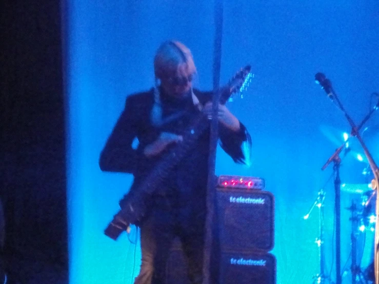 man holding guitar with stage lights in the background