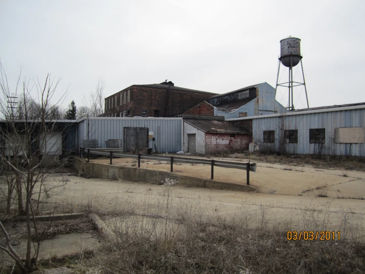 an empty industrial area with old buildings and a water tower