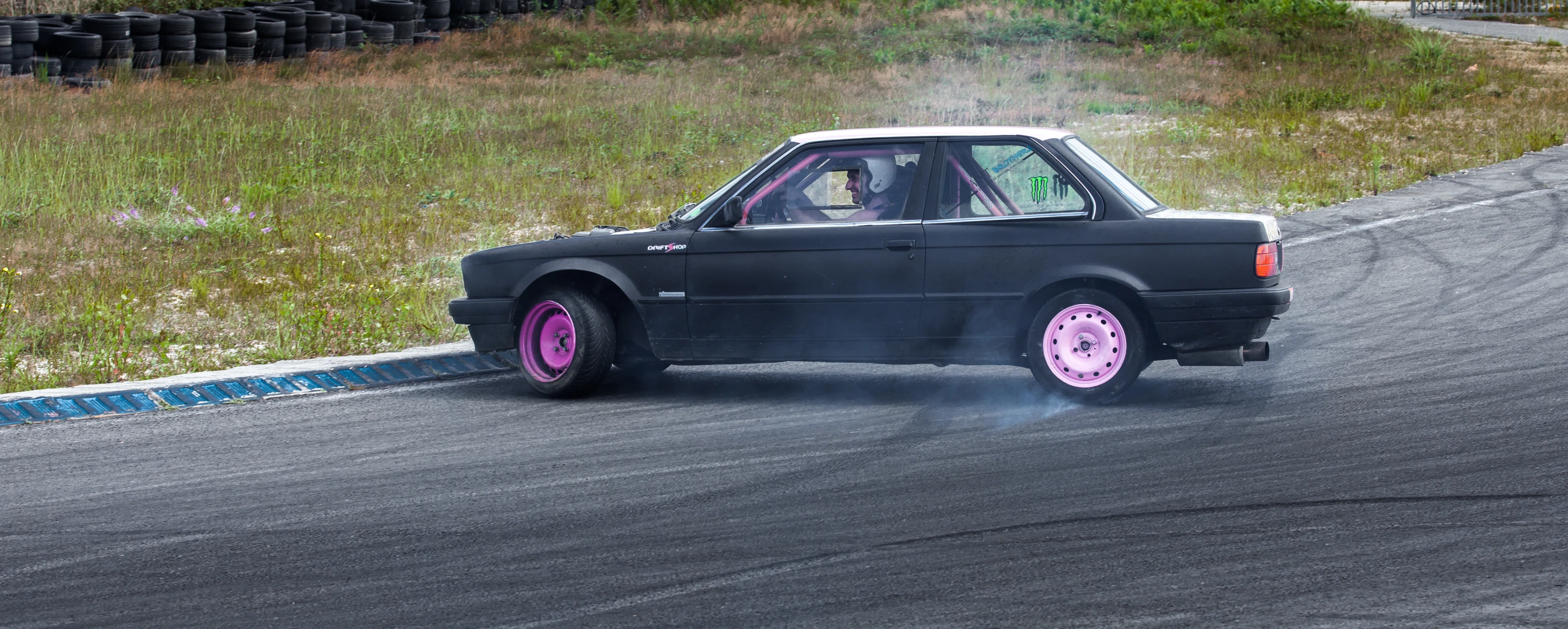 a small car driving down a track with smoke coming from its rear wheel