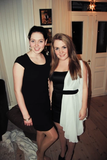 two beautiful young women standing next to each other in a room