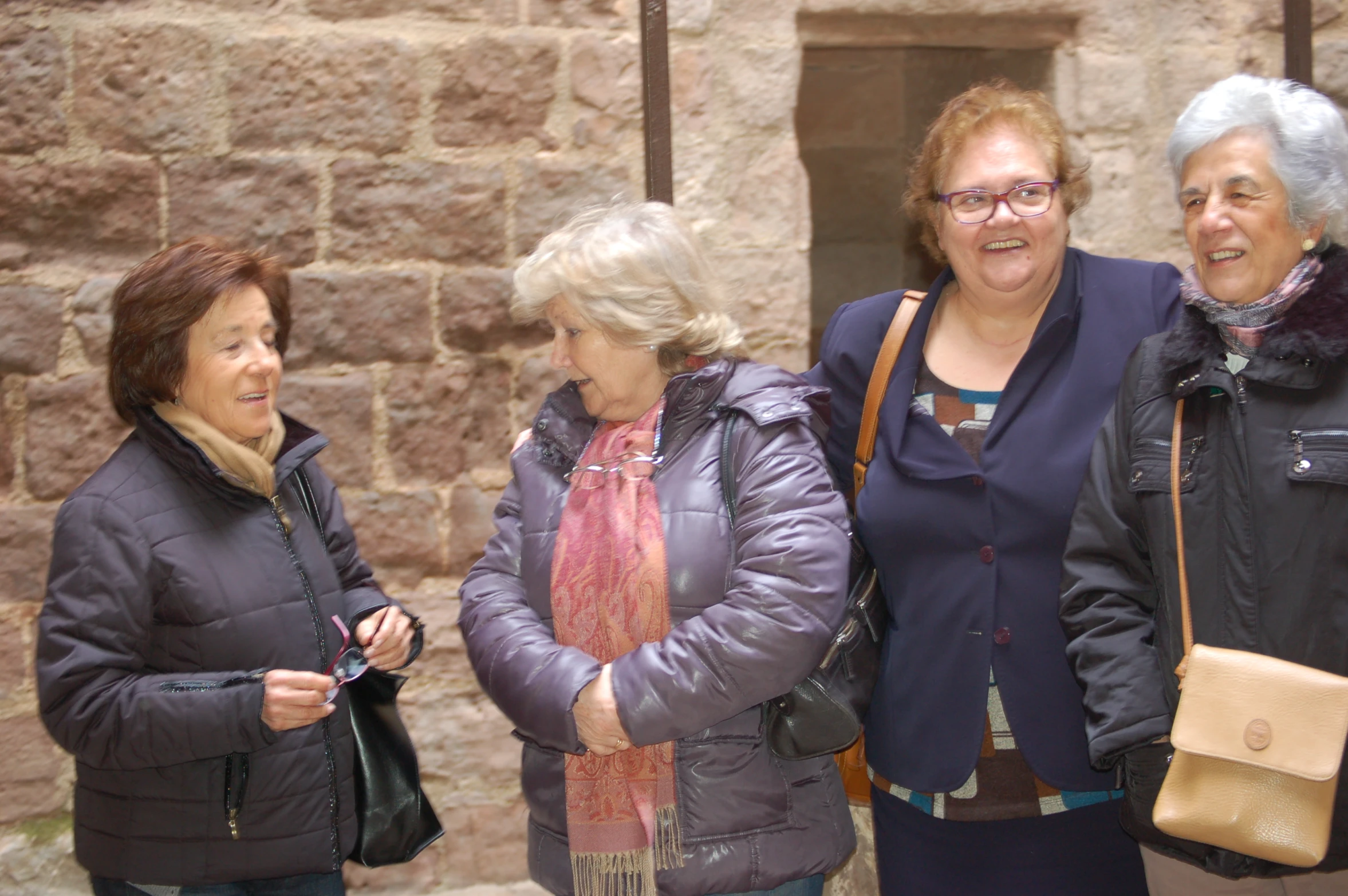 four women standing in front of a stone building