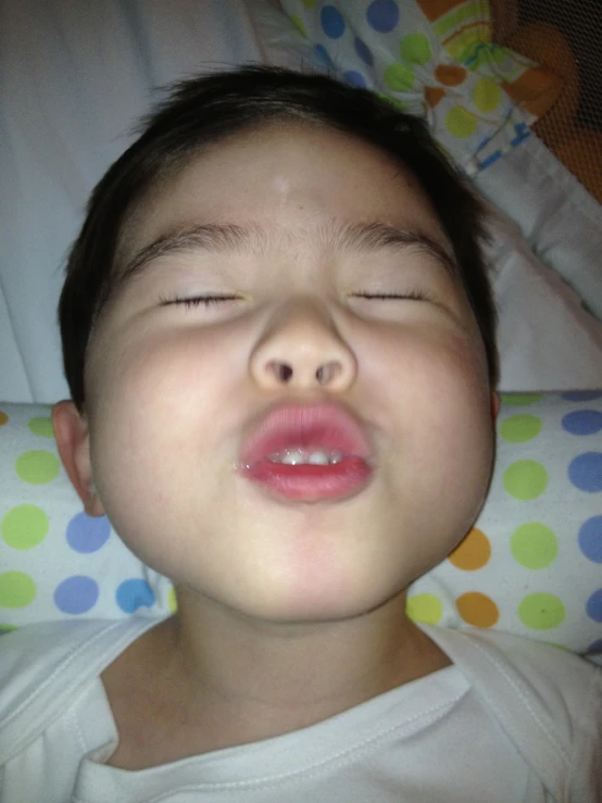 a close up of a child sleeping on a pillow