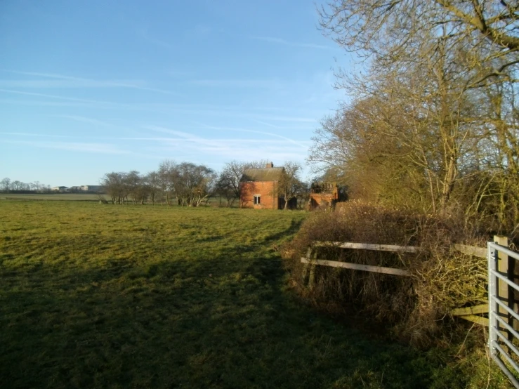 a grassy field with two fences and house