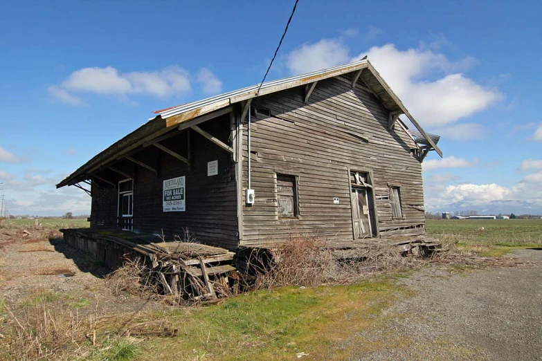 a large barn with a metal roof is next to an empty road