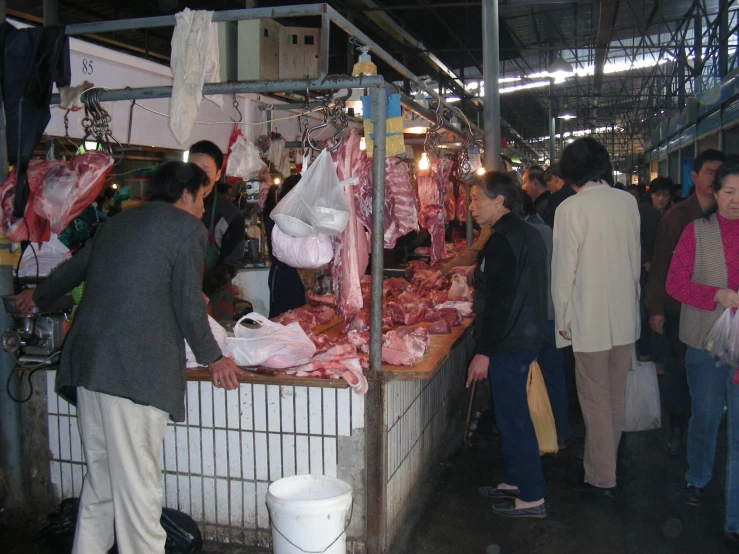 a bunch of people standing around a market stall
